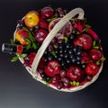 Wicker basket with fruit and a bottle of wine, beautifully decorated on a dark background. concept., congratulations for a holiday Royalty Free Stock Photo