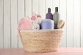 Wicker basket full of different baby cosmetic products, accessories and toy on pink wooden table Royalty Free Stock Photo