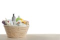Wicker basket full of different baby cosmetic products, bathing accessories and toy on wooden table against white background Royalty Free Stock Photo