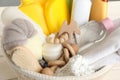 Wicker basket full of different baby cosmetic products, bathing accessories and toys on table, closeup
