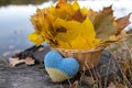 wicker basket full of fallen yellow-orange leaves with a yellow-blue Ukrainian knitted heart