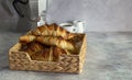 A wicker basket full of fresh-baked butter croissants and coffee.