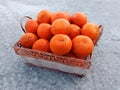 A wicker basket full of fresh orange fruits on the floor Royalty Free Stock Photo