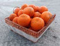 A wicker basket full of fresh orange fruits on the floor Royalty Free Stock Photo