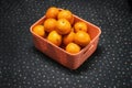 A wicker basket full of fresh orange fruits,  on a blue and white dotted background Royalty Free Stock Photo