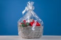 Wicker basket full of gift boxes on white wooden table against blue background Royalty Free Stock Photo