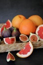 Wicker basket full of various fruits, colorful fruits, grapefruits and figs arranged on a natural bristle tray, sliced fruits, cit