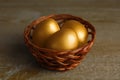 Wicker basket with golden eggs on wooden table, closeup Royalty Free Stock Photo