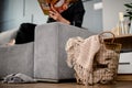 Wicker basket with handmade beige plaid inside standing near sofa