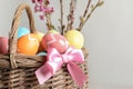 Wicker basket with painted Easter eggs and flowers on color background Royalty Free Stock Photo