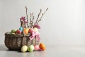 Wicker basket with painted Easter eggs and flowers on table Royalty Free Stock Photo
