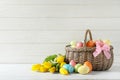 Wicker basket with painted Easter eggs and spring flowers on table Royalty Free Stock Photo