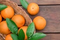 Wicker basket, ripe juicy oranges and green leaves on wooden table, flat lay Royalty Free Stock Photo