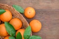 Wicker basket, ripe juicy oranges and green leaves on wooden table, flat lay. Space for text Royalty Free Stock Photo