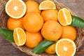 Wicker basket with ripe juicy oranges and green leaves on wooden table, top view Royalty Free Stock Photo