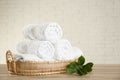 Wicker basket with rolled bath towels and green branch on wooden table Royalty Free Stock Photo