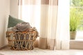 Wicker basket with rolled blankets and pillow, space for text. Idea for interior design