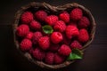 Wicker basket in shape of heartis filled to brim with luscious red raspberries, resting on wooden table. Royalty Free Stock Photo