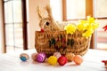 Wicker basket, straw Easter bunny and daffodils, crocheted eggs Royalty Free Stock Photo