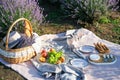 Wicker basket with tasty food and drink for romantic picnic in lavender field Royalty Free Stock Photo