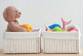 Wicker baskets with balls of knitting yarn and funny toys on table against light background Royalty Free Stock Photo