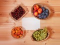 Wicker baskets full of ripe summer fruits on wooden table with empty card for your text. Royalty Free Stock Photo