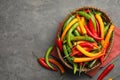 Wicker bowl with different chili peppers on grey table, flat lay Royalty Free Stock Photo