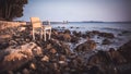 Wicker chair on rocky beach during sunset. Royalty Free Stock Photo