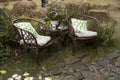 Wicker chairs in garden near the table with a vase with plants