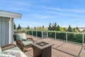 Wicker chairs surrounding a rectangular fire pit on an outdoor wooden deck with a fantastic view of Lake Washington