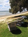 Wicker chairs under tree in front of beach Royalty Free Stock Photo