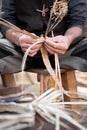 Old wicker craftsman with hands working in isolated foreground