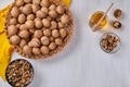 A wicker dish with walnuts stands on a white wooden table, next to a jar of honey and a bowl of peeled nuts Royalty Free Stock Photo