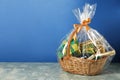 Wicker gift basket with wine on grey table against blue background. Space for text Royalty Free Stock Photo