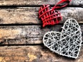 A wicker hearts a wooden background. Two red braided heart with hanging loop. White big heart. Two lovers. Valentine