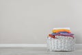 Wicker laundry basket with clean clothes on floor near light wall