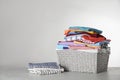 Wicker laundry basket with clean clothes on table against light background