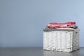 Wicker laundry basket with clean towels on table against color background Royalty Free Stock Photo