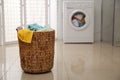 Wicker laundry basket full of colorful towels on floor in bathroom Royalty Free Stock Photo