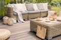 Wicker patio set with beige cushions standing on a wooden board Royalty Free Stock Photo