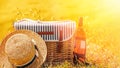 Wicker picnic basket, bottle of rose wine and straw hat on the meadow full of flowers Royalty Free Stock Photo