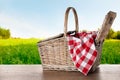 Wicker picnic basket and checkered blanket on table in park