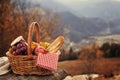 Wicker picnic basket with different products on rock in mountains. Space for text Royalty Free Stock Photo