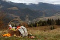 Wicker picnic basket with thermos, snacks and plaid in mountains on autumn day, space for text Royalty Free Stock Photo