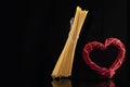 Wicker red heart and flying spaghetti on black background