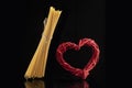 Wicker red heart and flying spaghetti on black background