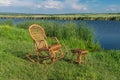 wicker rocking-chair standing next to small wicker hadnmade stool, on a Sura riverside waiting for any human to relax