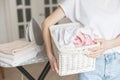 Wicker rustic basket with washed clothes in woman`s hand ready to ironing