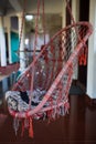 A wicker suspended summer chair hangs in the shade of tropical trees.