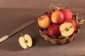 A wicker vase basket with fresh red apples on the table.